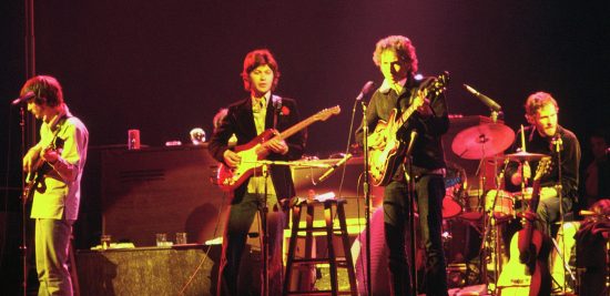Bob Dylan a The Band na turné 1974, Chicago USA. Zleva doprava: Rick Danko (baskytara), Robbie Robertson (kytara), Bob Dylan (kytara), Levon Helm (bicí) (Credit photo: Jim Summaria, Wikimedia, Creative Commons Attribution-Share Alike 3.0)